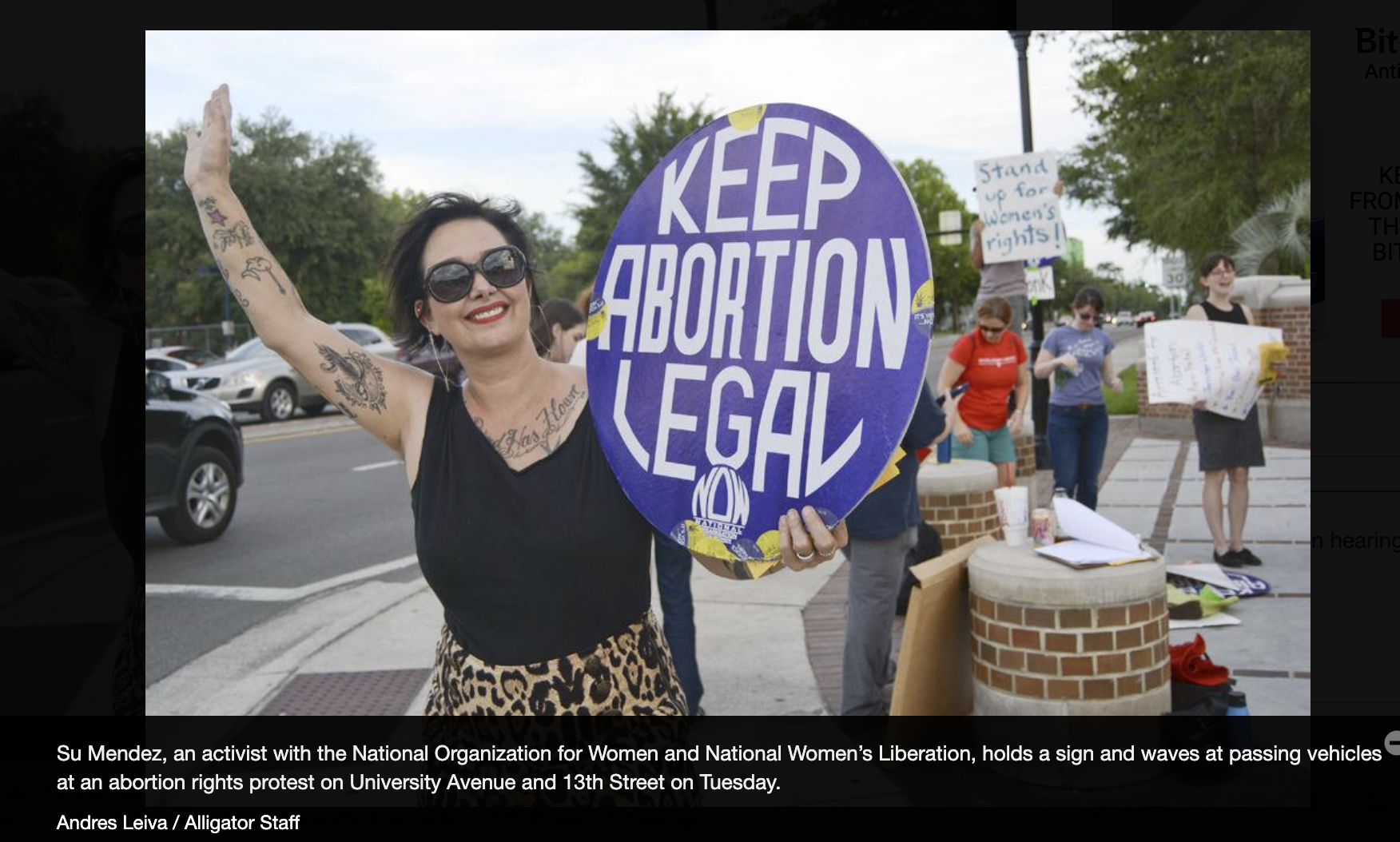 Sue Mendez waves at cars with Keep Abortion Legal sign